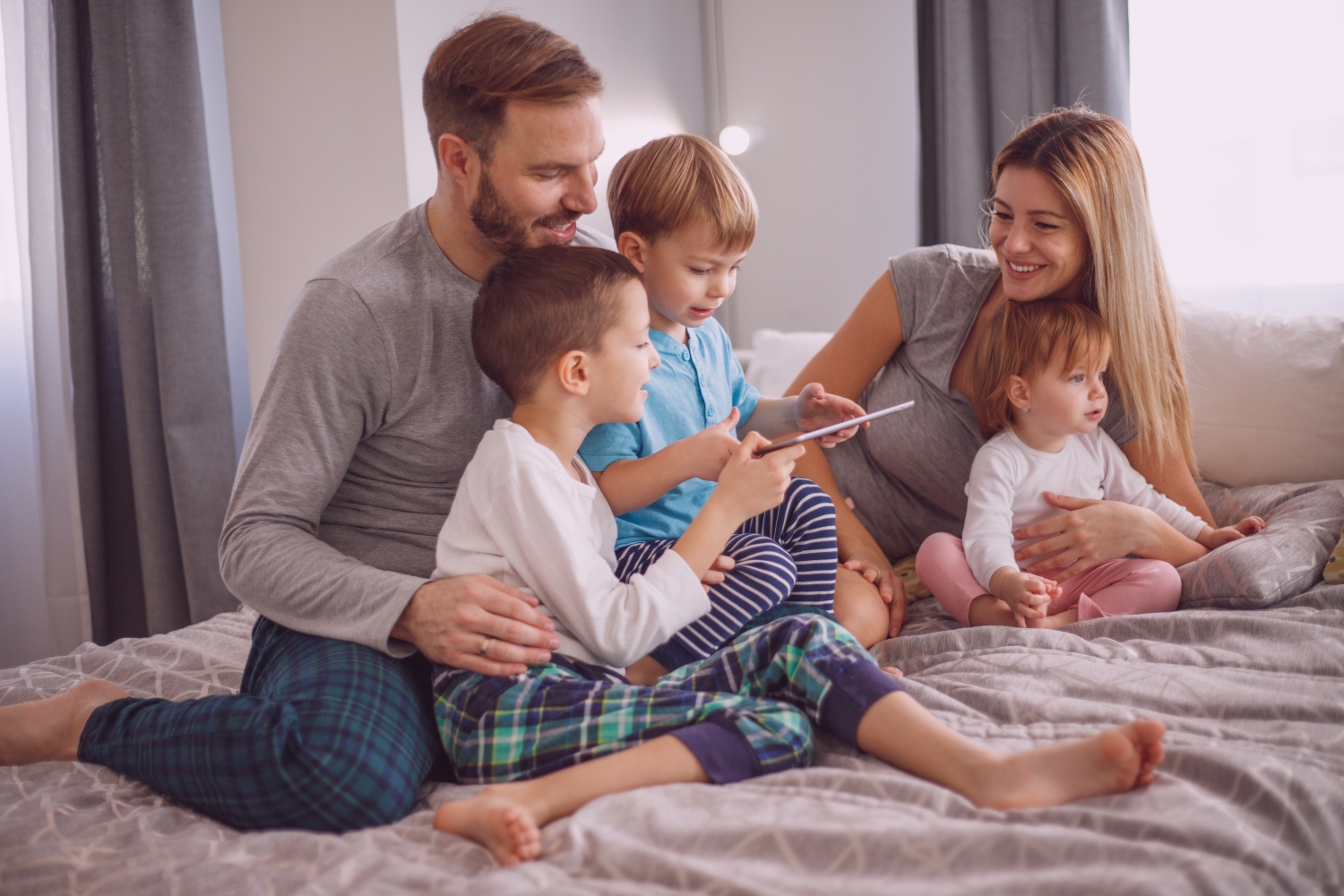 Man and woman couple with three young children on a bed