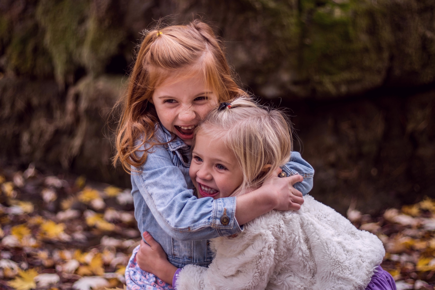 Two girls hugging in woods in autumn